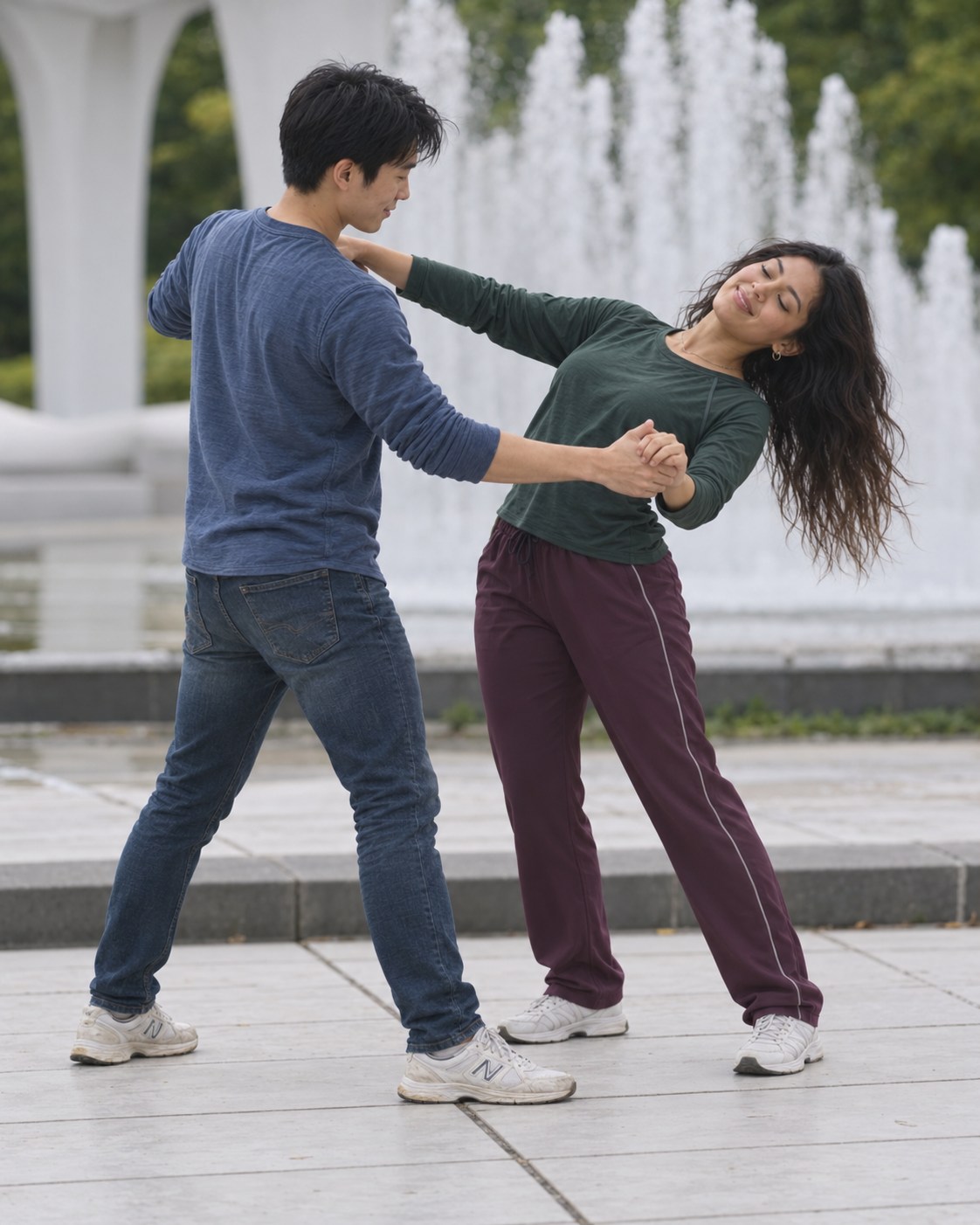 Two partners dancing beside a fountain, with the woman smiling with her eyes closed.