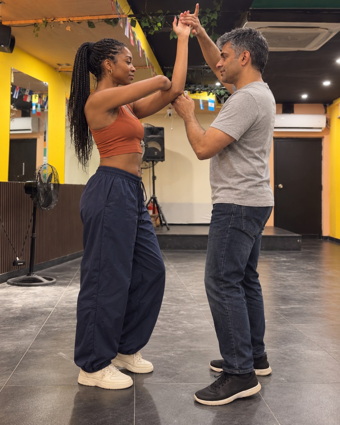 A Black woman and a South Asian man working through a raised-arm partner dance movement.